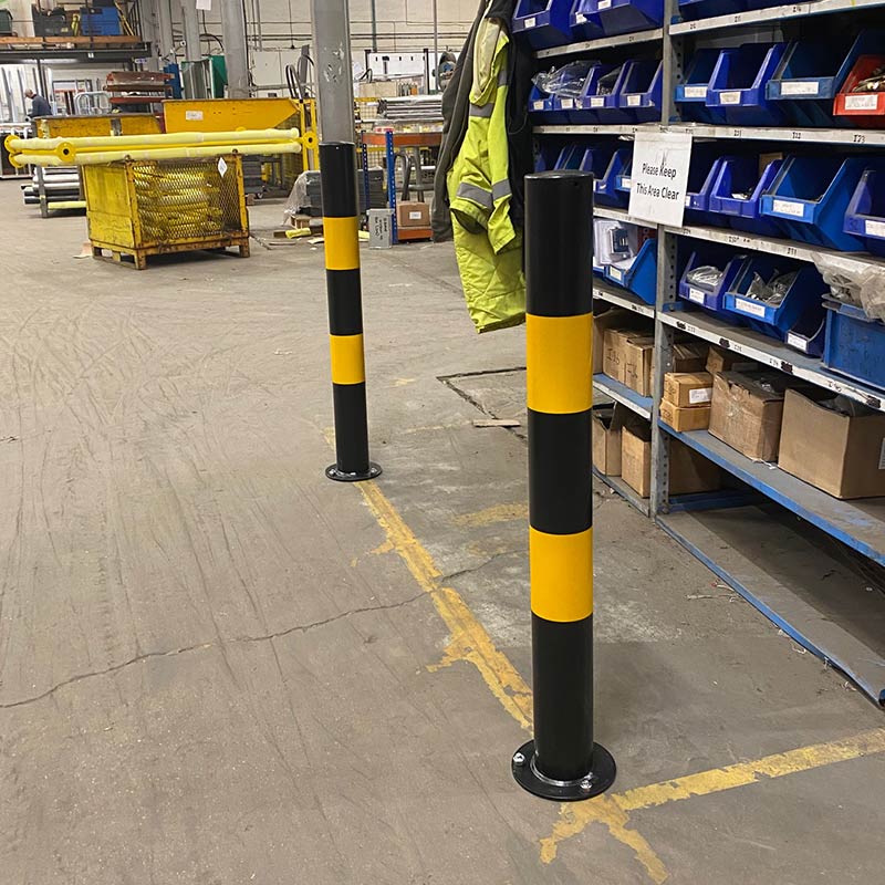 Black and yellow bolt down safety bollards in warehouse