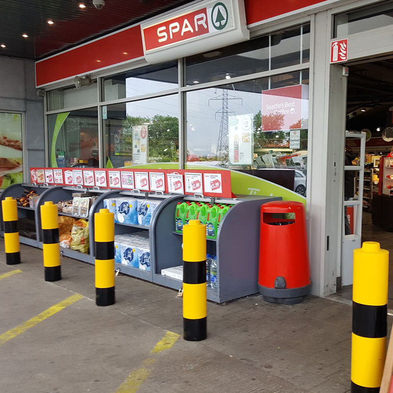 Yellow and black plastic bollard sleeves outside petrol station shop